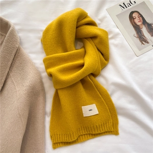 Detailed knit texture of a yellow winter scarf featuring a minimal eno fabric label