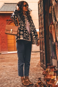 Scatto street style di una donna con giacca a motivi geometrici e jeans blu a gamba dritta