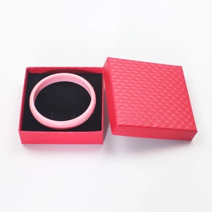 Detailed top view of a pink bracelet inside a red textured jewelry box with black lining