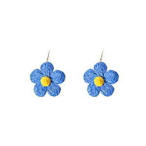 Detailed close-up of handmade woven raffia flower earrings in blue and yellow colors
