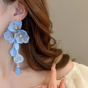 Close-up of blue floral tassel earrings with zircon details on a female model
