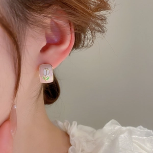 Detail view of pink tulip stud earrings featuring elegant floral patterns on a female model