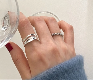 Detail of 925 sterling silver wavy and vintage beaded floral rings on model's hand