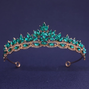 Elegant gold bridal crown with green marquise gemstones and crystals on dark blue background