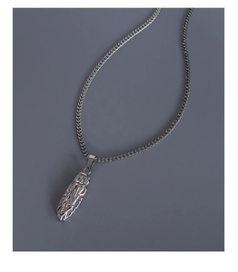 Macro shot of oval religious medallion pendant on silver-tone chain with detailed engraving