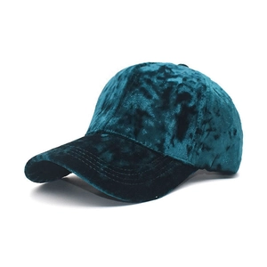 Detail of dark cyan velvet fabric texture and reinforced stitching on baseball cap brim