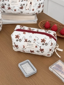 Detail shot of a quilted corduroy floral makeup bag on a wooden table with soft lighting