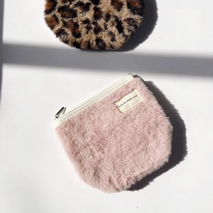 Detail of soft plush cosmetic bags with metal zippers in pink and leopard print colors