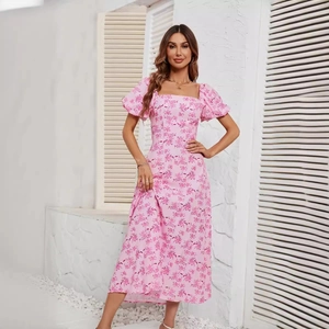 Pink floral midi dress with square neck and puff sleeves on model in resort setting