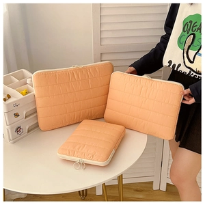 Detailed view of quilted laptop sleeves in orange-pink with various sizes and ring zippers