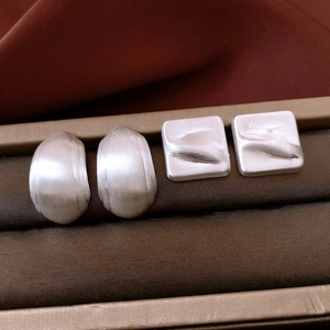 Gros plan sur des boucles d'oreilles argentées texturées sur un support en velours