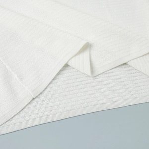 Close-up of white ribbed knit fabric showing soft texture and premium stitching details