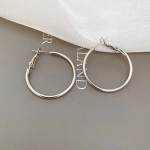 Flat lay of minimalist silver hoop earrings on grey background with white gauze