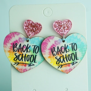 Detail of pink glitter and tie-dye wooden heart earrings with Back To School text