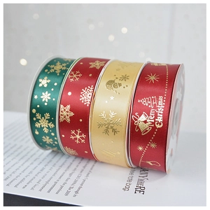 Close-up of 2.5cm satin Christmas ribbons with gold foil patterns and Merry Christmas text