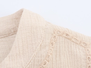 Macro view of beige blouse with floral eyelet embroidery and textured fabric detail