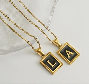 Macro detail of 18K gold plated stainless steel rectangle pendants with letters L and A