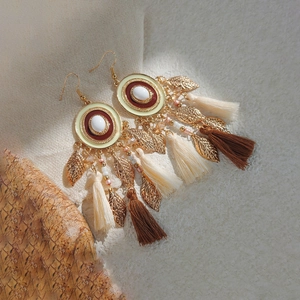 Detail of bohemian tassel earrings with gold leaf charms and multi-color beaded accents
