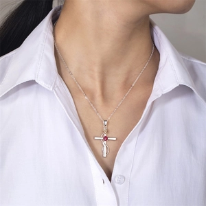 Detail of silver cross necklace with gold rose and red gemstone on a white shirt