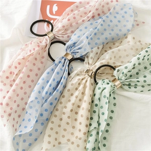 Close-up of four polka dot chiffon hair scrunchies with elegant gold buckle details