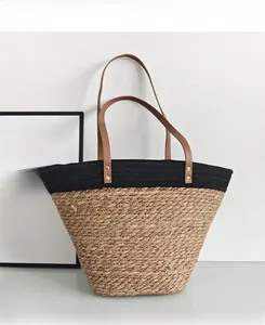 Detail of the woven straw texture with brown faux leather straps and gold rivets