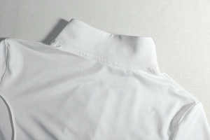 Close-up of white high neck collar and fine stitching on a slim fit ribbed knit top