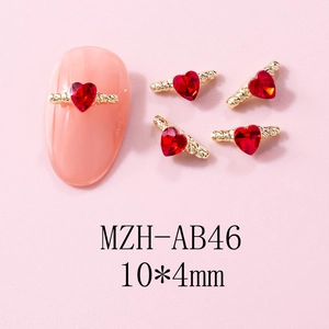 Detail of 10x4mm gold winged heart nail charms with red crystals for manicure