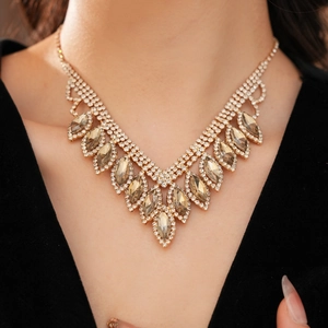 Close-up of V-shaped gold necklace with champagne marquise rhinestones on a model