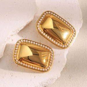 Macro view of geometric 18K gold plated earrings with pearl edge on stone background