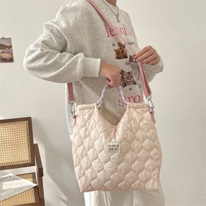 Détail du sac matelassé rose à motif floral avec poignée violette et bandoulière assortie
