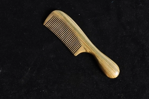 Detail view of the fine teeth and natural grain texture on a green sandalwood comb