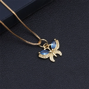 Macro view of a gold box chain necklace featuring a blue crystal butterfly pendant