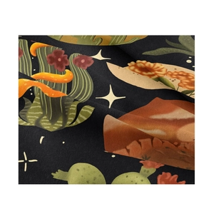 Close-up of soft black fabric with printed cactus flowers and taco motifs detail