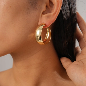 Close-up of a polished golden multi-layer chunky geometric hoop earring on model
