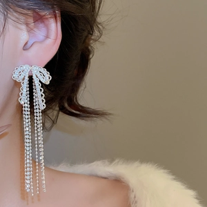 Silver bow tassel earrings with sparkling rhinestones worn by a model for an elegant look