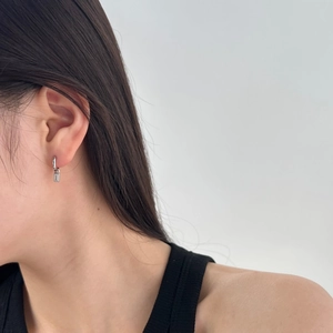 Close-up of minimalist S925 silver earring with geometric rectangular zircon pendant on ear