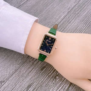 Detailed shot of rectangular rose gold watch with starry dial and green leather strap