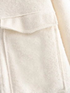 Close-up of thick creamy-white wool fabric with detailed pocket flap and fine stitching