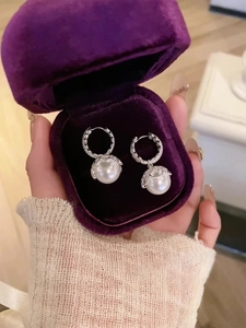 Detail of elegant pearl drop earrings with zircon lace in a velvet jewelry box