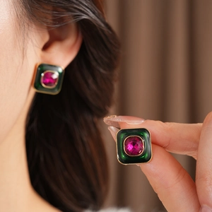 Detailed close-up of square vintage earrings featuring pink stone and green enamel
