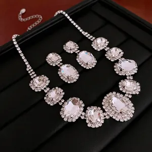 Elegant silver jewelry set with oval crystal pendant and matching drop earrings on black box