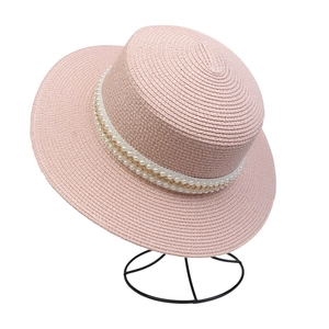 Detail of pink flat top straw hat featuring elegant white pearls and gold metal chain band
