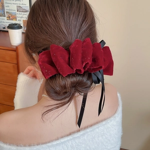 Détail d'une pince à cheveux en velours rouge avec paillettes et longs rubans de satin