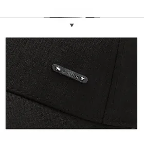 Close-up of black twill baseball cap fabric with a metal plate engraved with SPORT