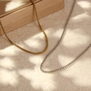 Collier Figaro en acier inoxydable plaqué or 18 carats en or et argent sur fond beige