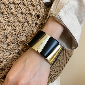 Detail of wide geometric black and gold acrylic bracelet with textured contrast
