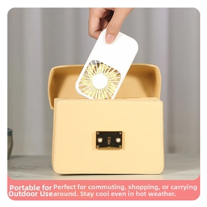 Detail showing a compact portable handheld fan being placed into a stylish leather bag