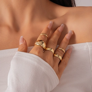 Detail of five-piece minimalist gold ring set featuring polished dome and slim bands