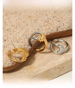 Detail of twisted knot gold and silver rings displayed on natural stone pedestals