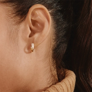 Detail of C-shaped gold hoop earrings featuring half smooth metal and half pave crystals